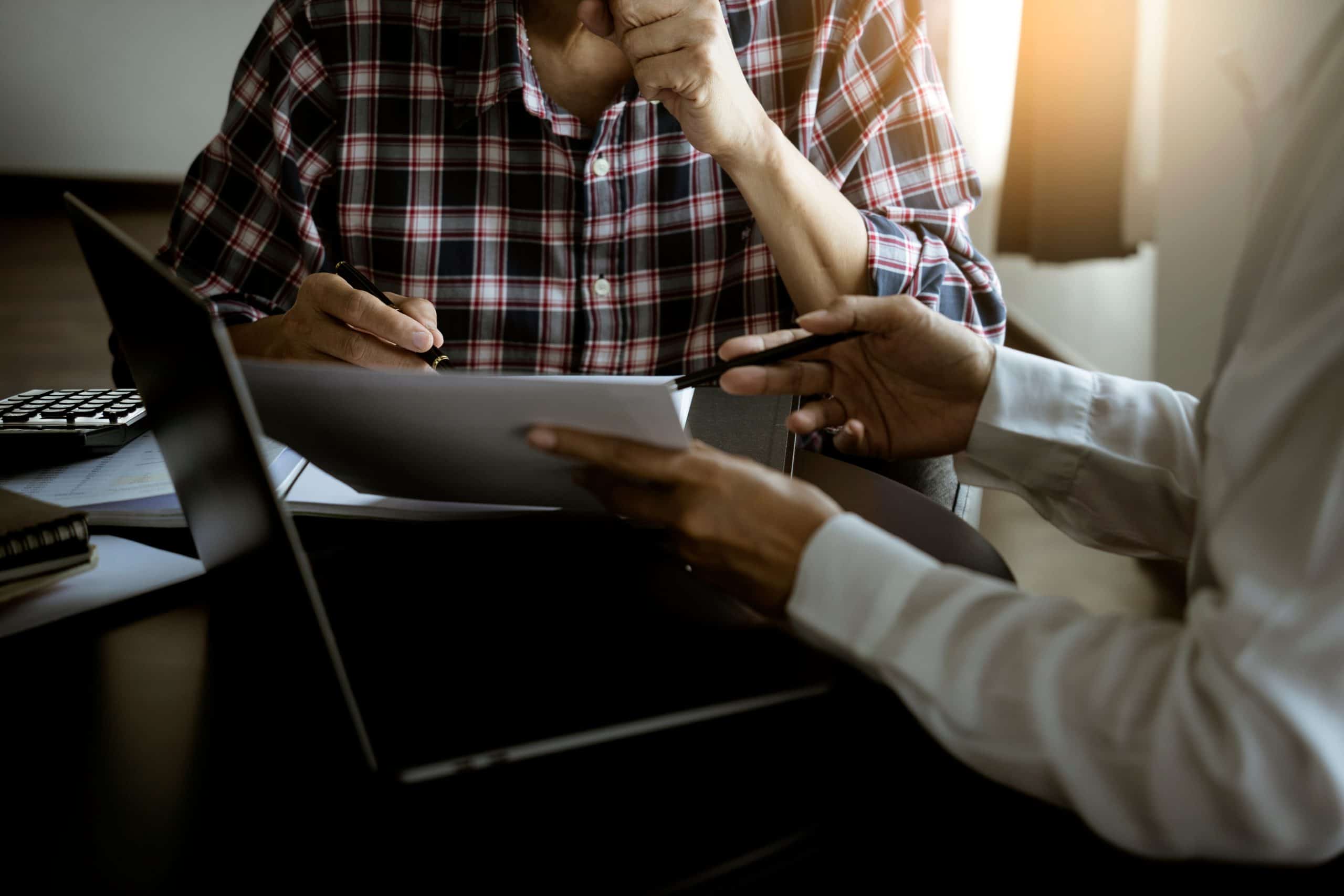 Foto de pessoas reunidas em uma mesa, analisando um computador