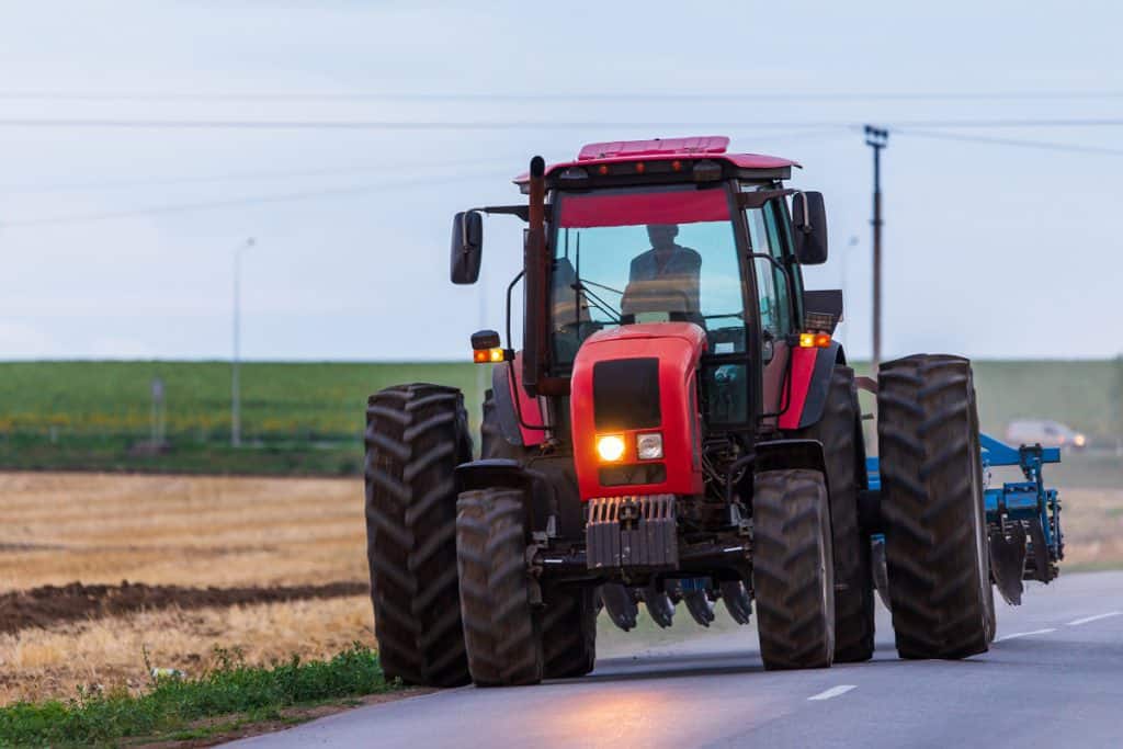 Imagem de máquina agrícola na estrada, no fim do dia
