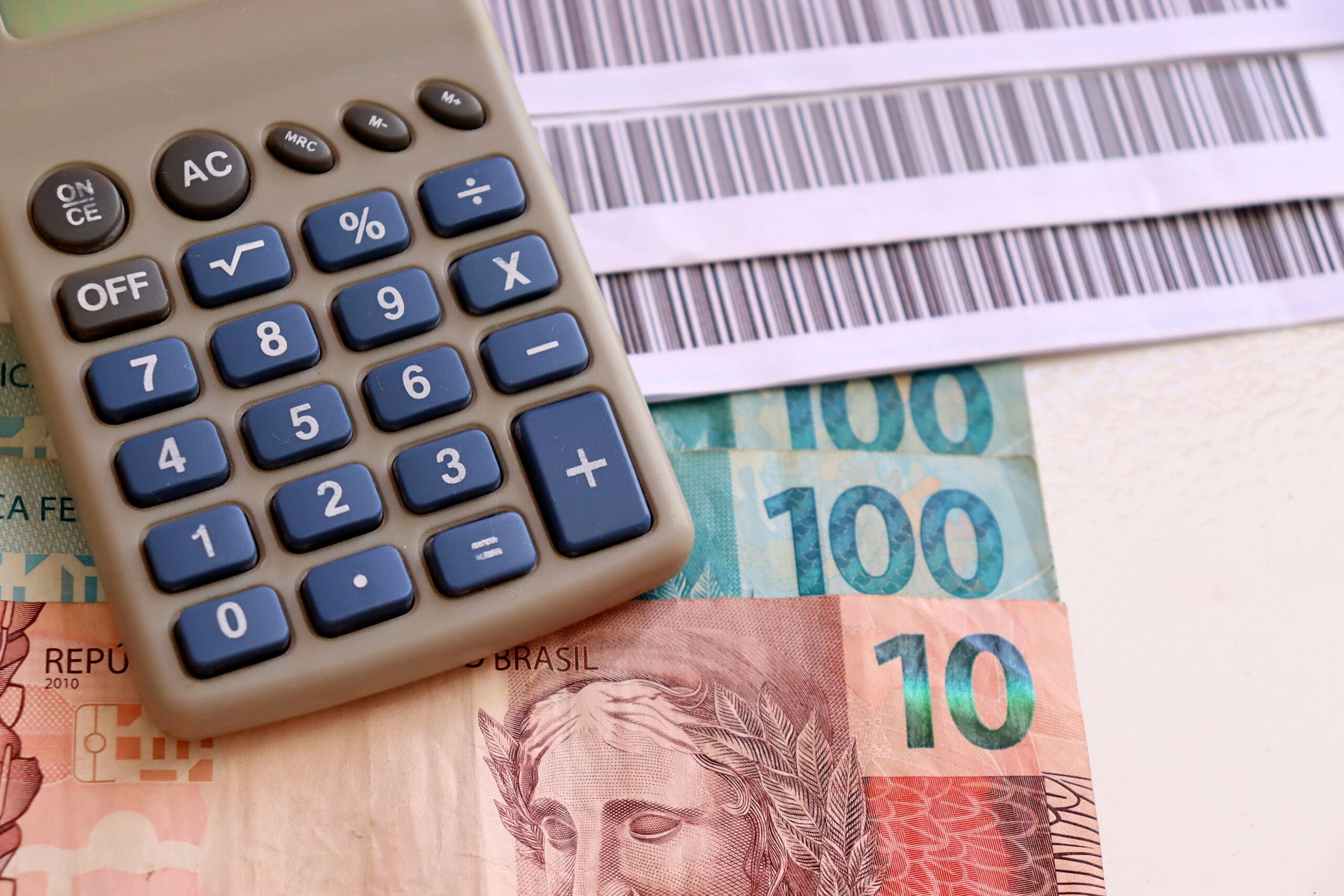 Calculadora, boletos e dinheiro representando o DIRPF para produtores ruais