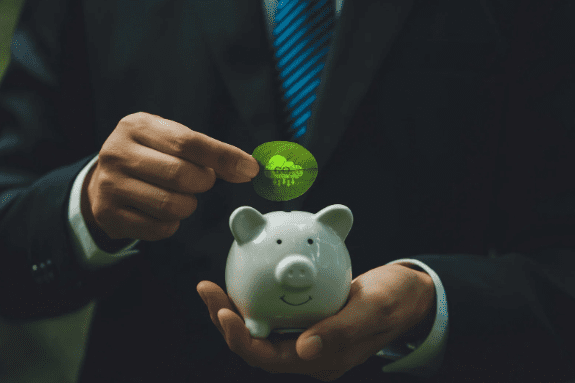 Homem de terno segurando um cofrinho branco em formato de porquinho enquanto deposita uma moeda simbólica feita de folha verde com o selo "eco", representando investimento em sustentabilidade e crédito de carbono.